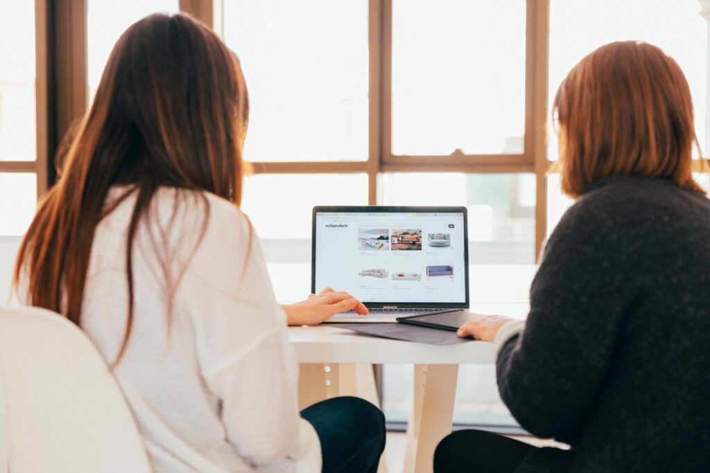 Zwei Frauen am PC richten ihre LinkedIn Profile ein um ihre Karriere zu stärken.